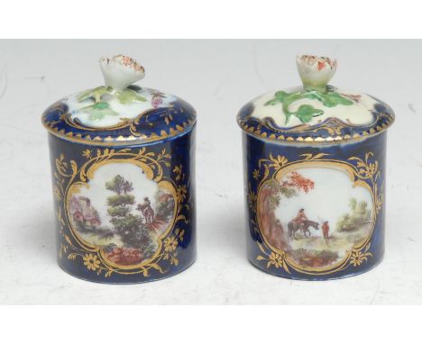 A pair of Derby cylindrical pots and covers, decorated with shaped gilt cartouches with figures in a landscape, the verso wit