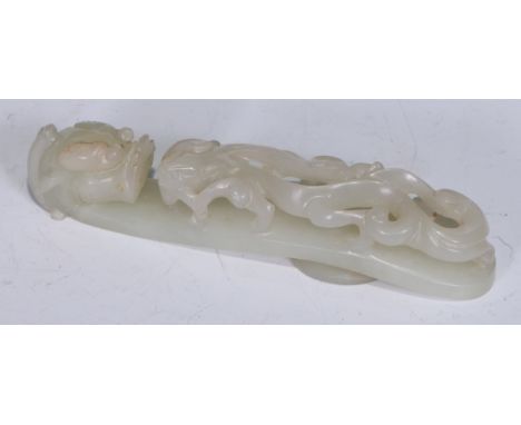 A Chinese pale celadon/white jade belt hook, late Qing dynasty, of typical serpentine form, carved and pierced with chilong c