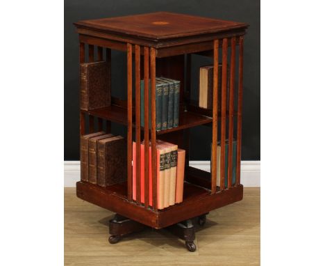 A Sheraton Revival satinwood crossbanded mahogany revolving bookcase, moulded top inlaid with a batwing patera, above an arra