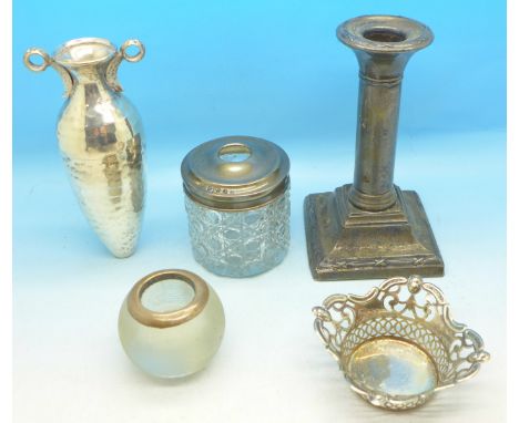 A silver candlestick, a silver topped jar, a silver rimmed match striker, a pierced white metal dish and a white metal posy h