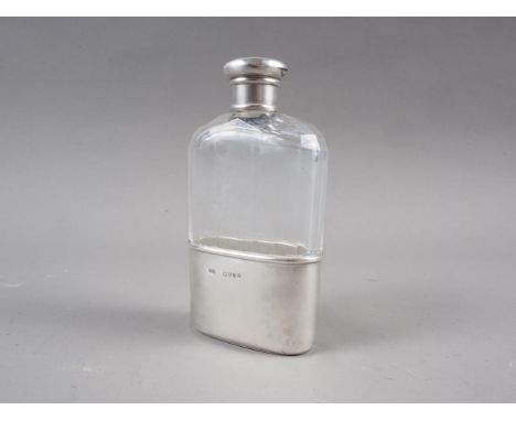 A clear faceted glass hip flask with silver cup and white metal cap, 4 1/2" high 