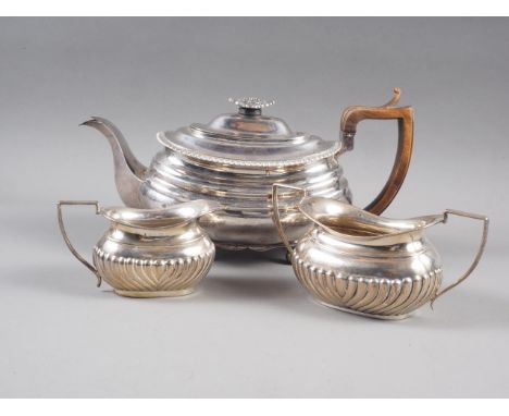 A Georgian silver teapot with hardwood handle, on four spherical feet, and a matching cream jug and sugar basin, 25.1oz troy 