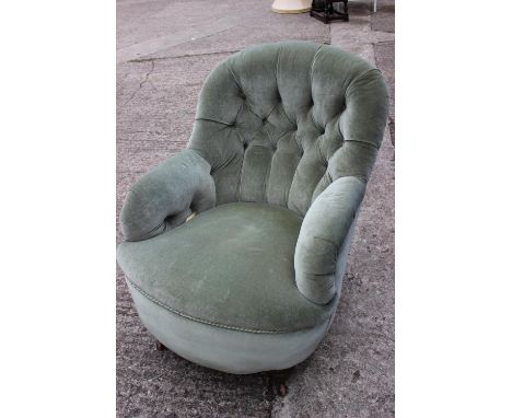 A 1920s chair, button upholstered in a sage green Dralon, on turned and castored supports 