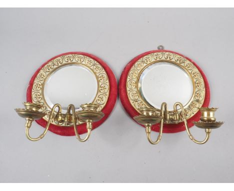 A pair of two-light brass framed wall sconces with bevelled mirrored backs and embossed decoration, 9" dia 