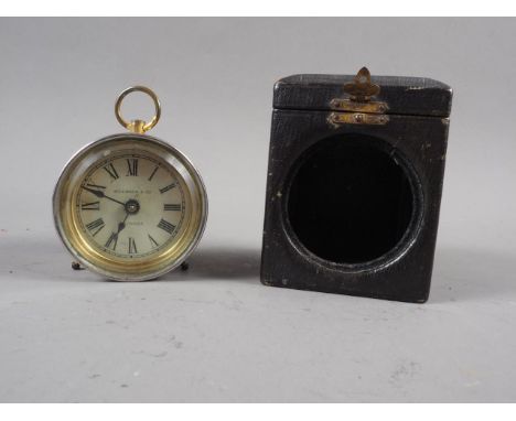A circular white metal cased travel clock with white enamel dial and Roman numerals, in leather hinged box, a Pelham Puppet "
