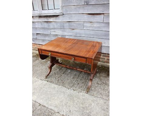 An early 19th century mahogany sofa table with acanthus carved brackets, on shaped sabre leg supports and brass castors, unit