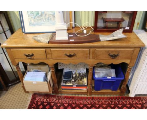 A pine dresser base, rectangular top over three in-line drawers, turned &amp; block forelegs united by a box shelf under tier