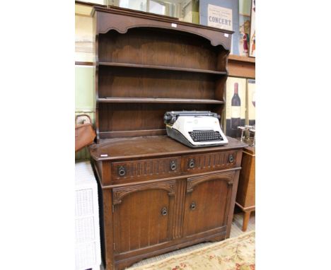A reproduction oak finish dresser, having twin shelf plate rack back the base having two in-line drawers over two cupboard do