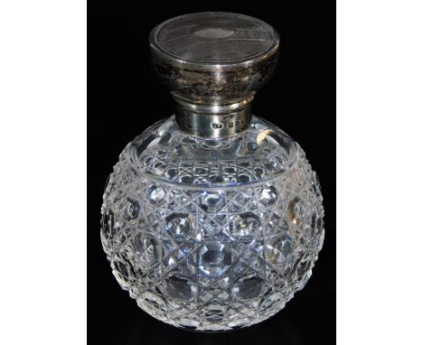 An early 20thC cut glass perfume bottle, with engine turned silver lid, 10cm high.