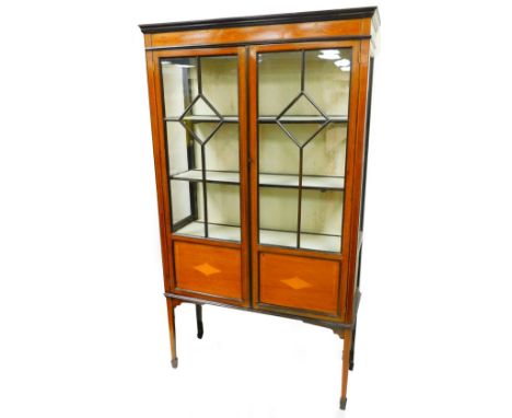 An Edwardian mahogany display cabinet, with an inlaid bell flower and bow frieze above two astragal glazed doors and diamond 