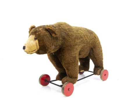 A post-war Steiff bear on wheels,  with brown mohair, clear and black glass eyes with brown backs, inset blonde mohair muzzle