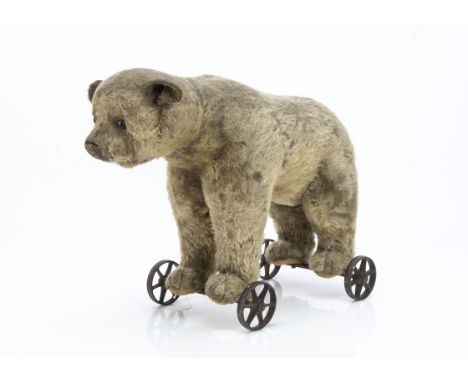 An early Steiff bear on wheels circa 1910,  with blonde mohair, black boot button eyes, pronounced muzzle, remains of black s