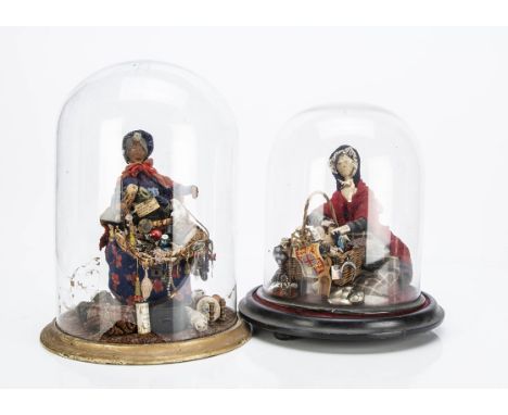Two Pedlar dolls under glass domes, a pegged wooden doll in red cloak seated with basket of wares; and another with brown clo
