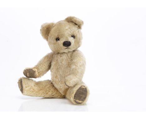 A post-war Chad Valley teddy bear,  with blonde mohair, brown and black glass eyes, pronounced muzzle, black stitched nose an