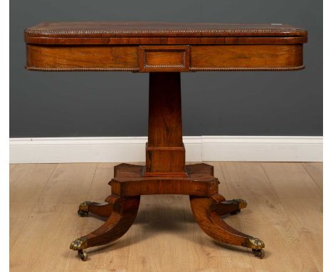 A Regency style rosewood fold over card table with beaded decoration on central square pillar and four outswept supports with