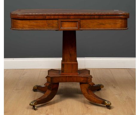 A Regency style rosewood fold over card table with beaded decoration on central square pillar and four outswept supports with