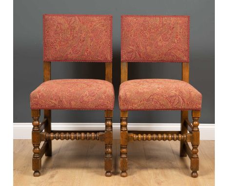 A pair of Jacobean style oak upholstered side chairs with bobbin turned stretchers to the front, each 44cm wide x 91cm highCo