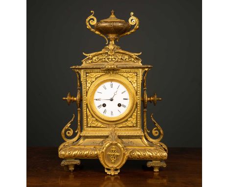 A late 19th century French gilt metal mantle clock with an urn finial and enamelled dial with roman numerals, the movement in