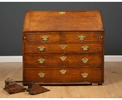 A 19th century oak bureau the drop front over fitted interior and two short and three long drawers with brass escutcheons and