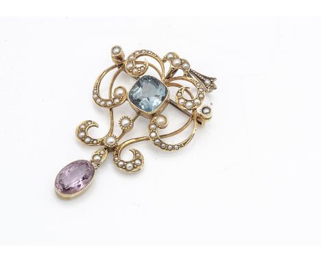 A 15ct gold tourmaline and seed pearl Art Nouveau pendant or brooch, the cushion cut blue tourmaline within a scrollwork seed