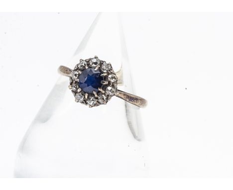 A sapphire and diamond cluster ring, the circular cut claw set sapphire surrounded by old cut diamonds all in yellow gold, di