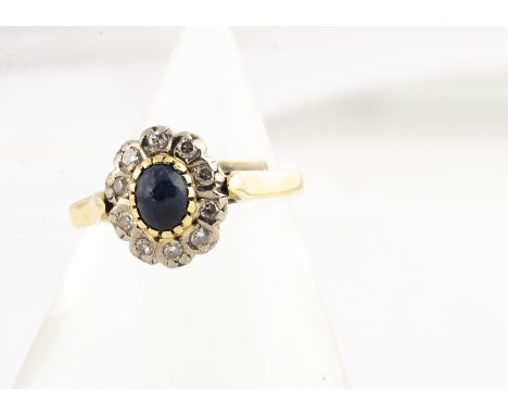 A continental sapphire and diamond cluster ring, all in yellow metal marked 750, with cabochon central sapphire surrounded by