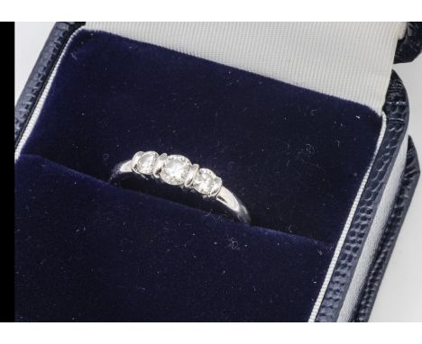 A platinum and diamond three stone ring, the brilliant cuts in bracket setting, on a rounded platinum shank, total diamond we