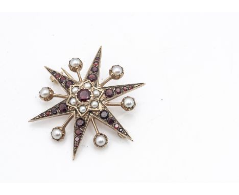 A gold , garnet and pearl star brooch, the six point star with garnet points centred with a cluster of pearls with central ci