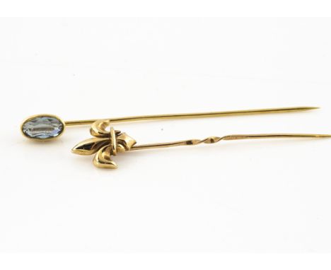 An 18ct gold aquamarine stick pin, the oval mixed cut in collet setting, 1.6g together with a 9ct gold example with fleur de 