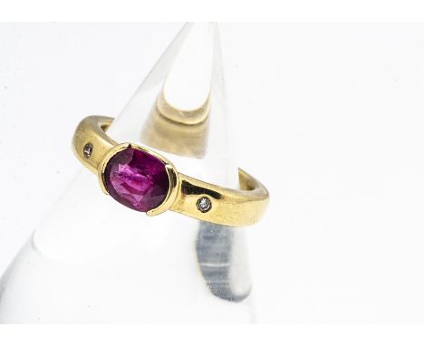 A contemporary 18ct gold ruby and diamond dress ring, the oval mixed cut ruby in tension collar setting flanked by two small 