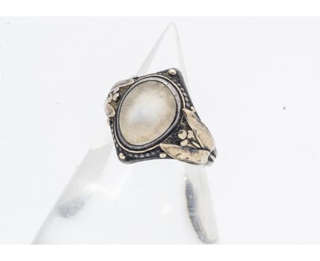 An Arts and Crafts silver and gold moonstone set signet ring, the cabochon oval moonstone within a navette shaped setting wit