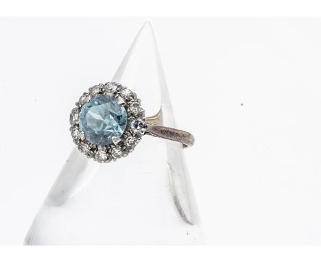 A zircon and diamond cluster dress ring, the circular mixed cut blue zircon in a four claw setting surrounded by eight cut di