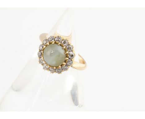 An 18ct gold chrysobel, cats eye and diamond cluster ring, the central green stone with white cats eye surrounded by a bezel 