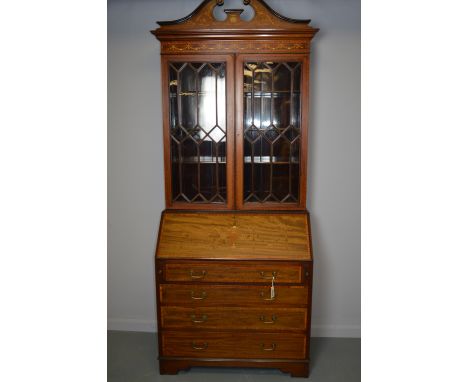 An Edwardian style secretaire bookcase, the projecting cornice, inlaid with ribbons and swags and pair of astragal glazed doo