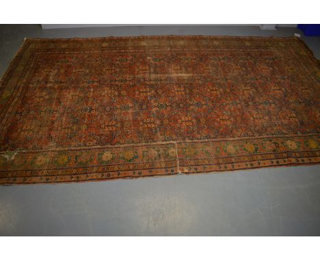 A Caucasian carpet, the madder ground with repeating foliate design, contained within a border of stylised flowerheads, 404 x