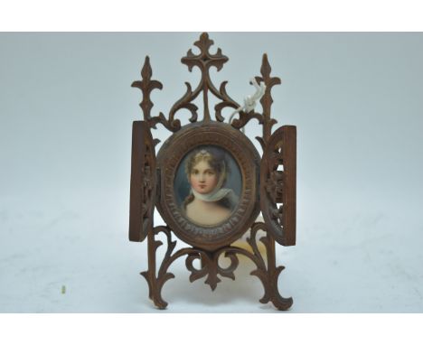 A porcelain miniature bust portrait of a lady, on an ornate carved wood easel stand.