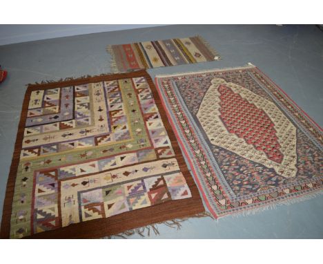 Three kelim rugs, the first with madder medallion, enclosing repeating stylised flowerhead, contained within a repeating bord