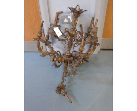 An ornate brass rococo style chandelier, with scrollwork and acanthus leaf branches; a wall light fitting; cut glass lustres;