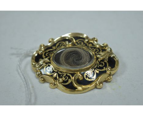 A 19th Century black enamel yellow metal memorial brooch, with hair set plaque to centre surrounded by floral scrolls, with p