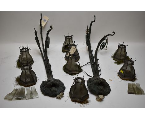A pair of vintage cast metal lion mask pattern wall lights, each with three scrolling arms; and eight pendant light shades wi