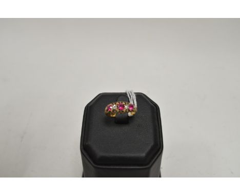 A ruby and diamond ring, the three graduated rubies (possibly synthetic) parted by two brilliant cut diamonds, on gold shank,