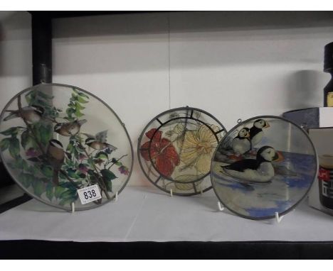 Three circular glass light catchers including two featuring birds.