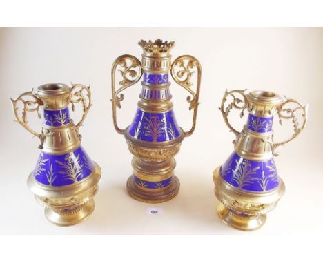 A Victorian brass garniture of three vases in the Gothic Revival style with cast floral decoration and blue enamel bands pain
