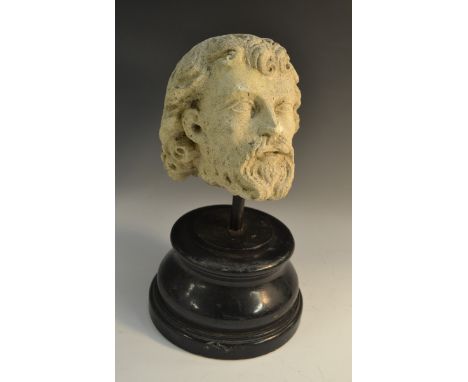 A post-Medieval limestone sculptural fragment, carved as the head of a bearded saint, 19cm high, ebonised display plinth