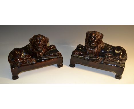 A pair of 19th century treacle glazed terracotta models, of recumbent lions, seated to left and right, rectangular bases with