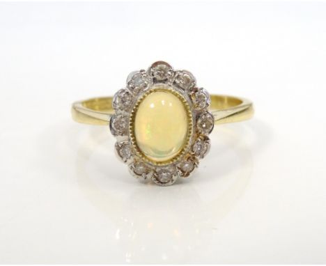 OPAL AND DIAMOND CLUSTER RINGthe central oval cabochon opal in twelve diamond surround, on eighteen carat gold shank, ring si