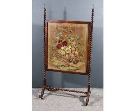A Late Victorian Walnut Framed Rectangular Fire Screen, inset with floral needlework panel, on bobbin turned uprights with tu