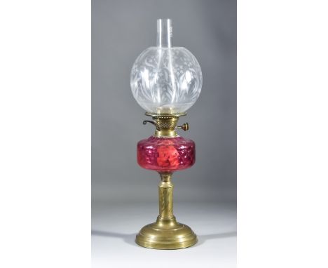 A Victorian Brass Table Oil Lamp, with moulded cranberry glass reservoir on engraved column and circular moulded base, 14.25i