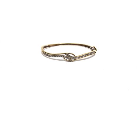 A DIAMOND SET HINGED BANGLE  stamped '375', the cross over style frontis piece set with thirty six single cut diamonds, the b