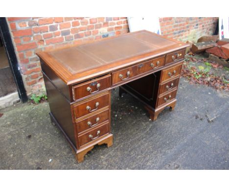 A reproduction twin pedestal desk with tooled leather top over nine drawers, on bracket supports, 47" wide, a matching two-dr